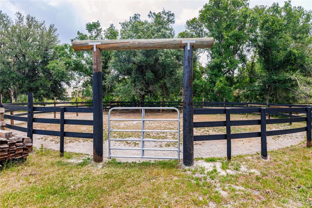 A metal gate stands between two tall wooden posts in a fenced outdoor area — 9325 SW LIPE ROAD, ARCADIA, FL