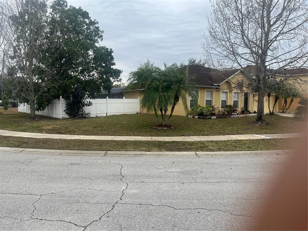 A yellow single-story house with a white fence and palm trees sits on a corner lot — 5091 PLYMOUTH TURTLE CIRCLE, ST CLOUD, FL