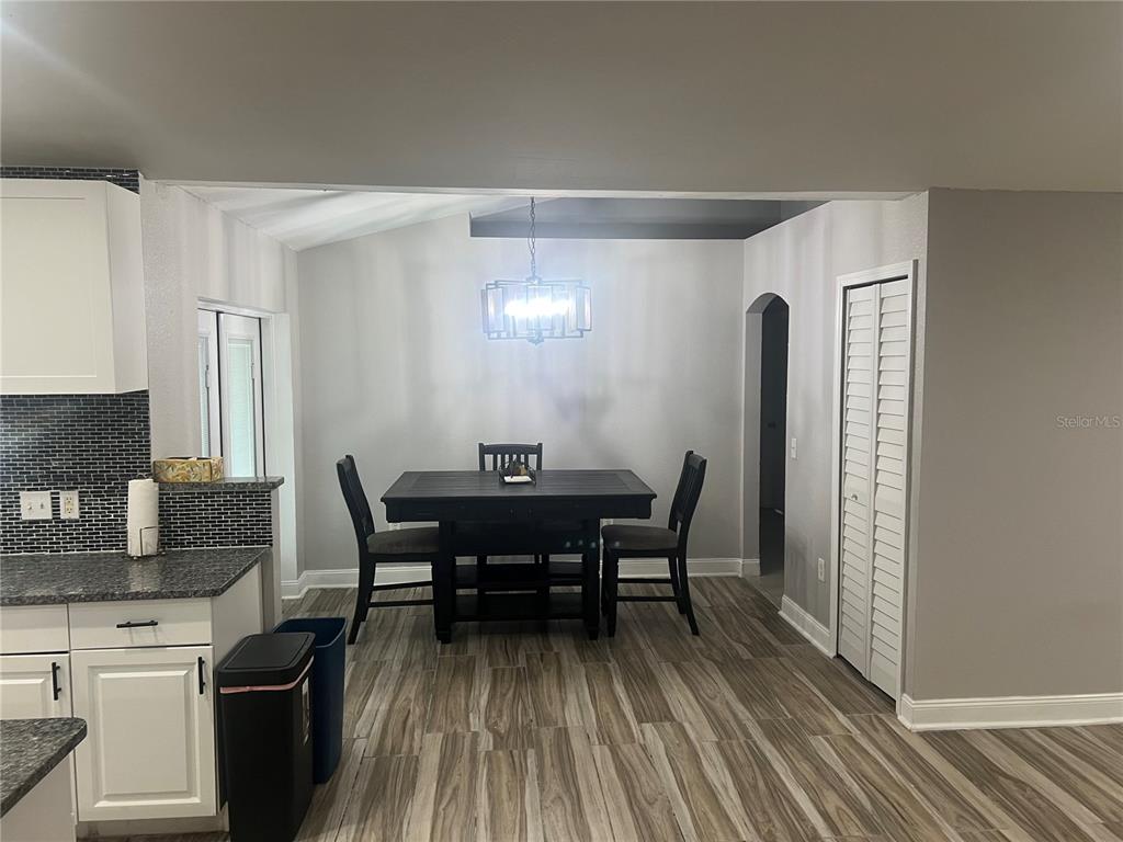 A dining area features a dark wood table, chairs, and a modern chandelier on wood-look flooring — 5091 PLYMOUTH TURTLE CIRCLE, ST CLOUD, FL