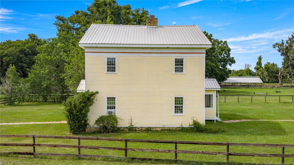 A two-story yellow farmhouse with a metal roof sits in a grassy fenced pasture — 13939 N US HIGHWAY 441 UNIT (yellow house), CITRA, FL