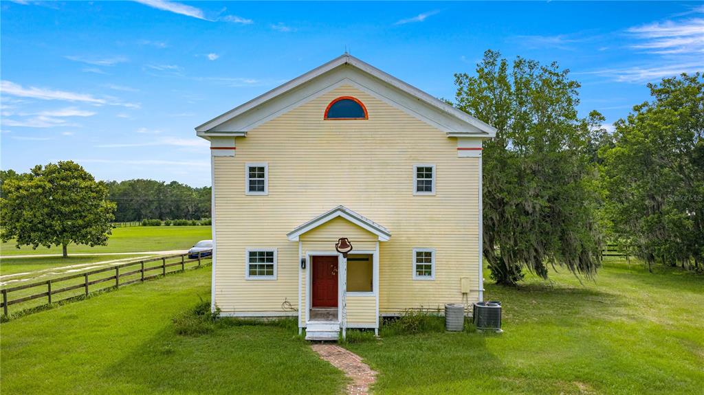 A yellow two-story house with a red front door sits on a grassy lot — 13939 N US HIGHWAY 441 UNIT (yellow house), CITRA, FL