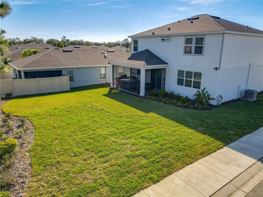 The backyard of a two-story house features a screened-in patio and a grassy lawn — 2248 CANOPY TERRACE BOULEVARD, DELAND, FL
