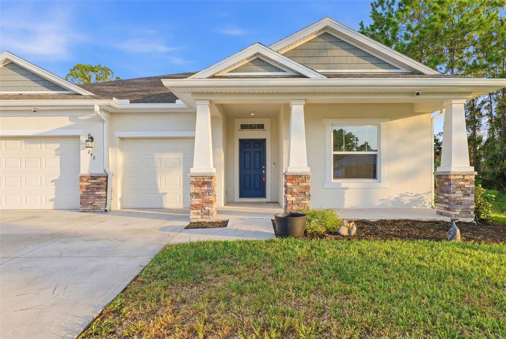 A bright, virtually staged entryway features light wood flooring, a console table, and a round mirror — 242 HERITAGE STREET SW, PALM BAY, FL