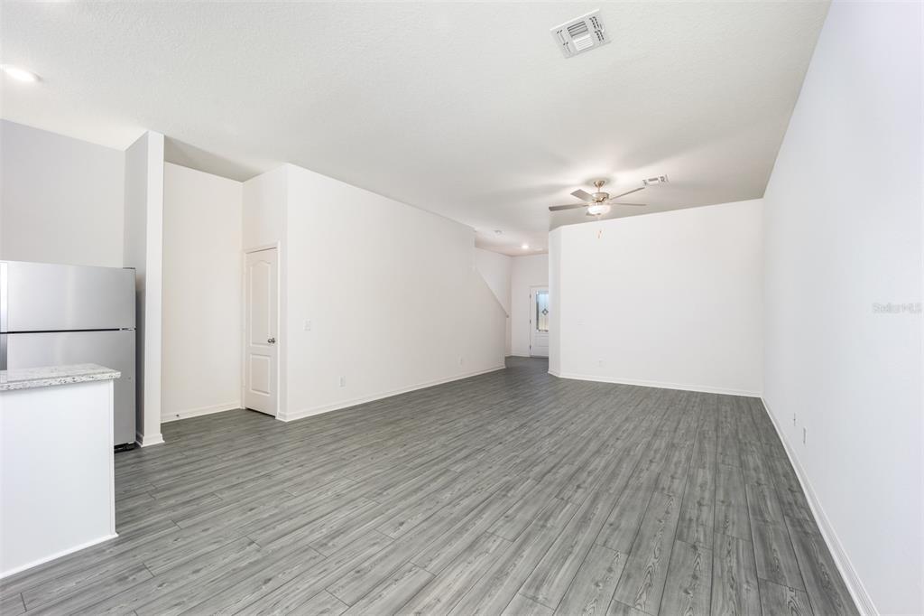 An open-concept living area features gray wood-look flooring, white walls, and a ceiling fan — 691 POPPY LANE, DUNDEE, FL