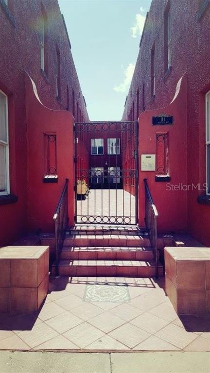 A gated entrance leads to a courtyard between two red stucco buildings with tiled stairs — 111 S NEWPORT AVENUE UNIT 15, TAMPA, FL
