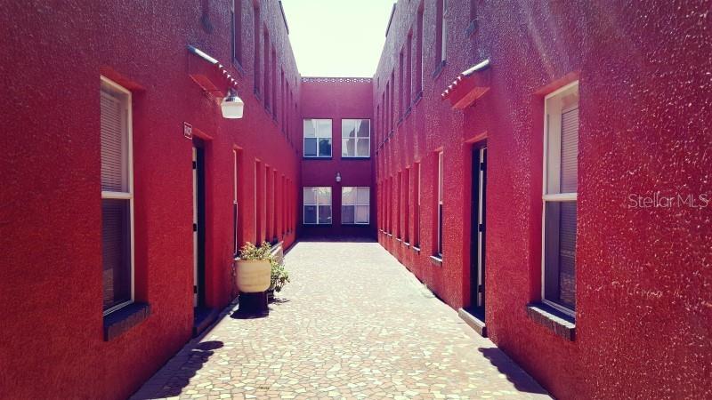 A narrow outdoor courtyard between two red stucco buildings with a paved walkway — 111 S NEWPORT AVENUE UNIT 15, TAMPA, FL