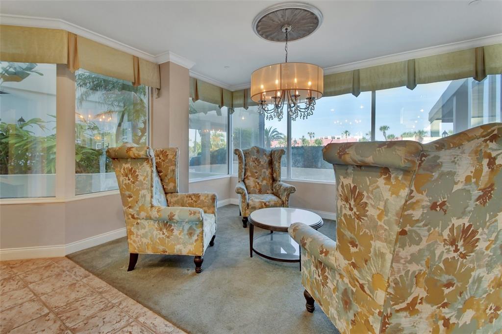A sunroom features three floral wingback chairs, a round coffee table, and large windows — 2937 S ATLANTIC AVENUE UNIT 2008, DAYTONA BEACH SHORES, FL