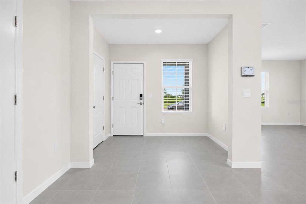 An entryway with light gray tile flooring, a white front door, and a window — 1021 SILVERBELL TRAIL, ST CLOUD, FL