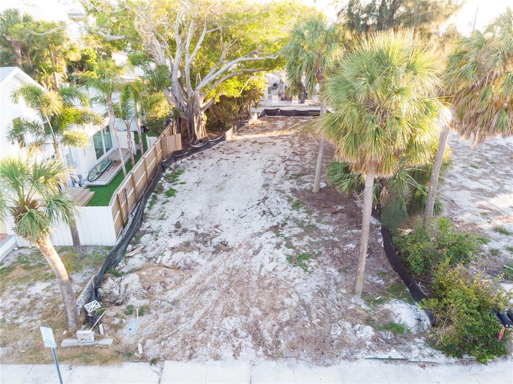 An aerial view shows a vacant, sandy residential lot bordered by a fence and trees — 110 4TH AVENUE, ST PETE BEACH, FL
