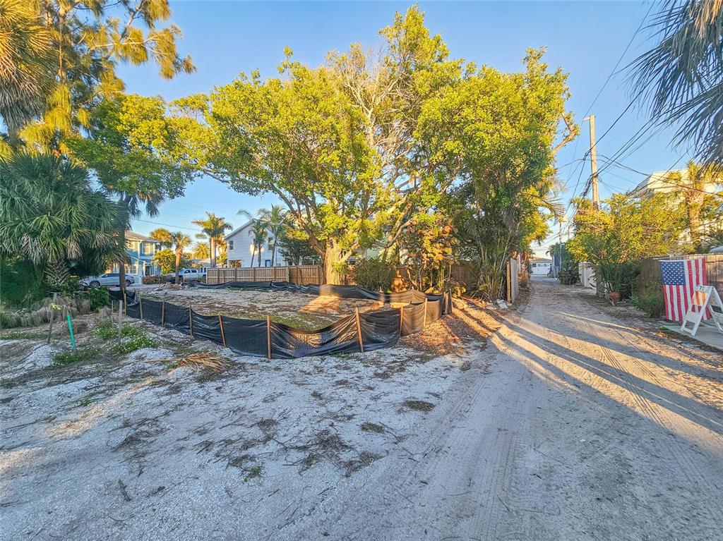 A vacant lot with a silt fence sits next to a sandy alleyway and trees — 110 4TH AVENUE, ST PETE BEACH, FL