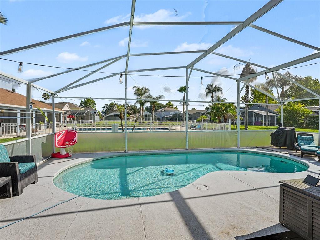 A screened-in patio features a kidney-shaped swimming pool and a small basketball hoop — 550 BUCKINGHAM CIRCLE, DAVENPORT, FL