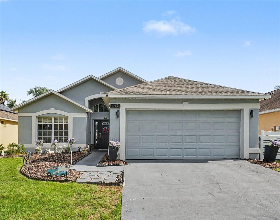 A single-story house with a gray stucco exterior, a two-car garage, and a front walkway — 550 BUCKINGHAM CIRCLE, DAVENPORT, FL