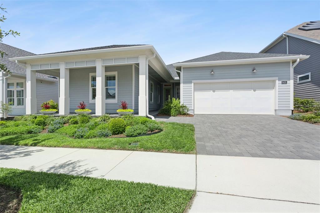 A light blue house with a white-pillared porch, a two-car garage, and a paved driveway — 6410 TRAILBLAZE BEND, ST CLOUD, FL