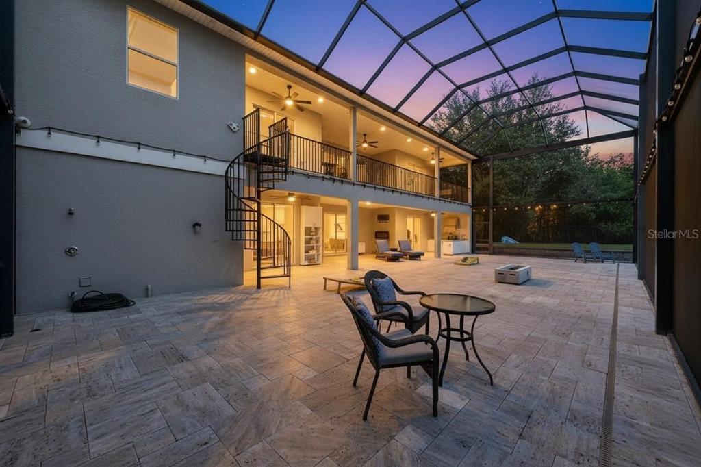 A spacious covered patio features stone flooring, a spiral staircase, and a second-story balcony — 3410 26TH AVENUE E, BRADENTON, FL