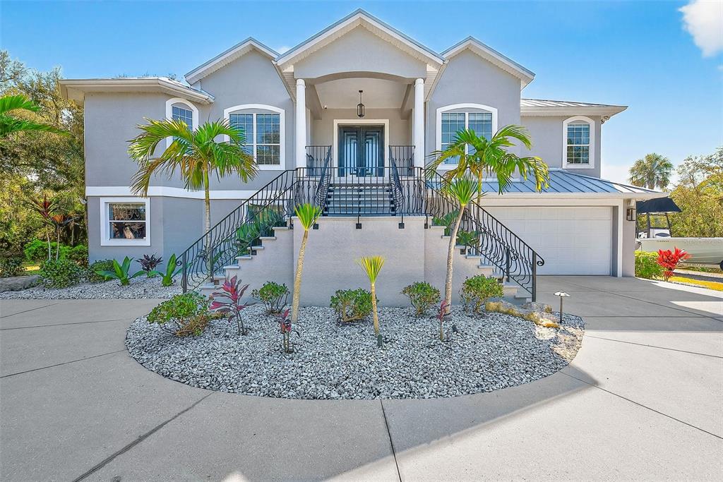 A two-story gray house with a raised front entrance, double staircase, and circular driveway — 3410 26TH AVENUE E, BRADENTON, FL