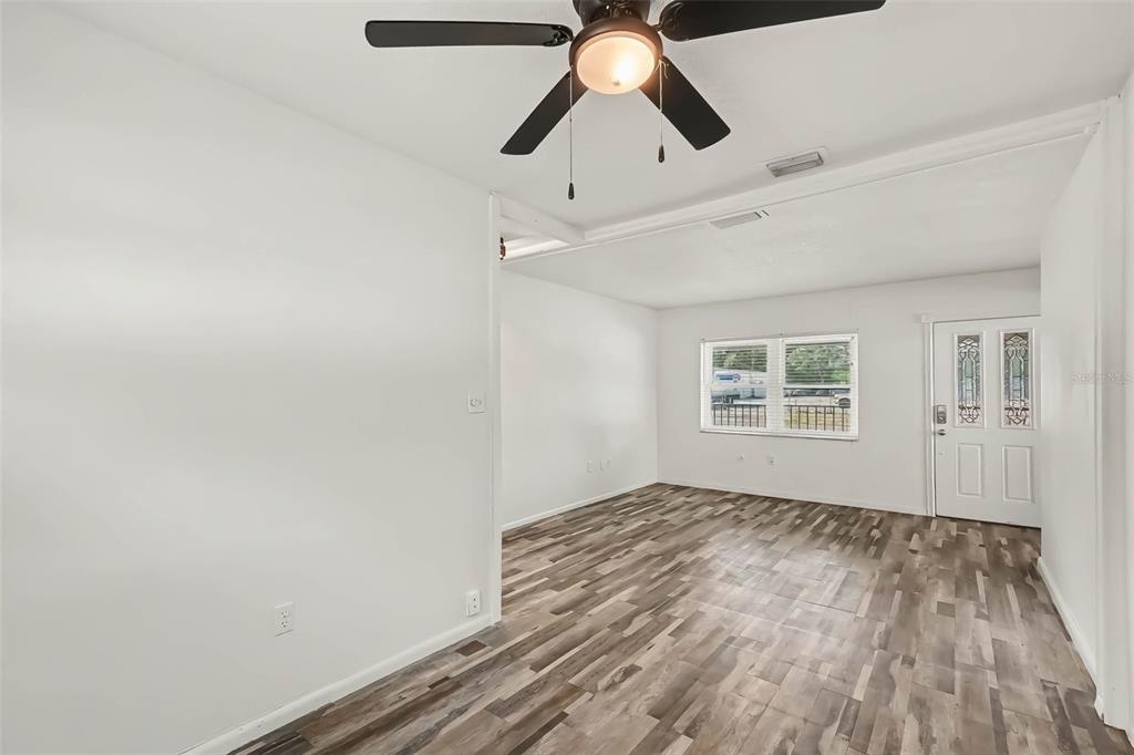 An empty room features white walls, a ceiling fan, and wood-look laminate flooring — 313 MILLER MAC ROAD, APOLLO BEACH, FL
