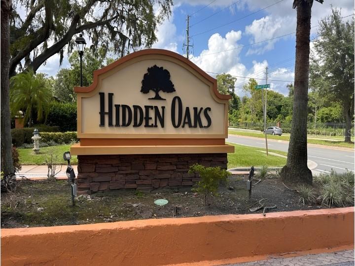 A stone-based monument sign for Hidden Oaks stands near a road with trees and landscaping — 7413 BELLE RIVER COURT UNIT 3, WINTER PARK, FL