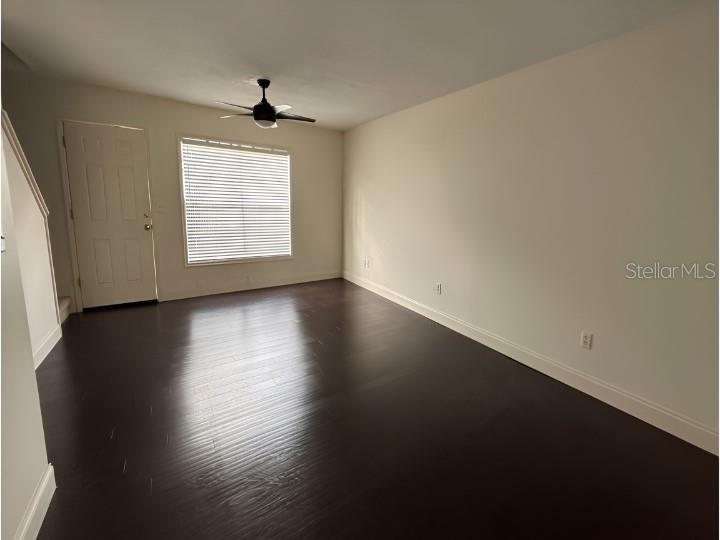 An empty room features dark wood flooring, white walls, a ceiling fan, and a window — 7413 BELLE RIVER COURT UNIT 3, WINTER PARK, FL
