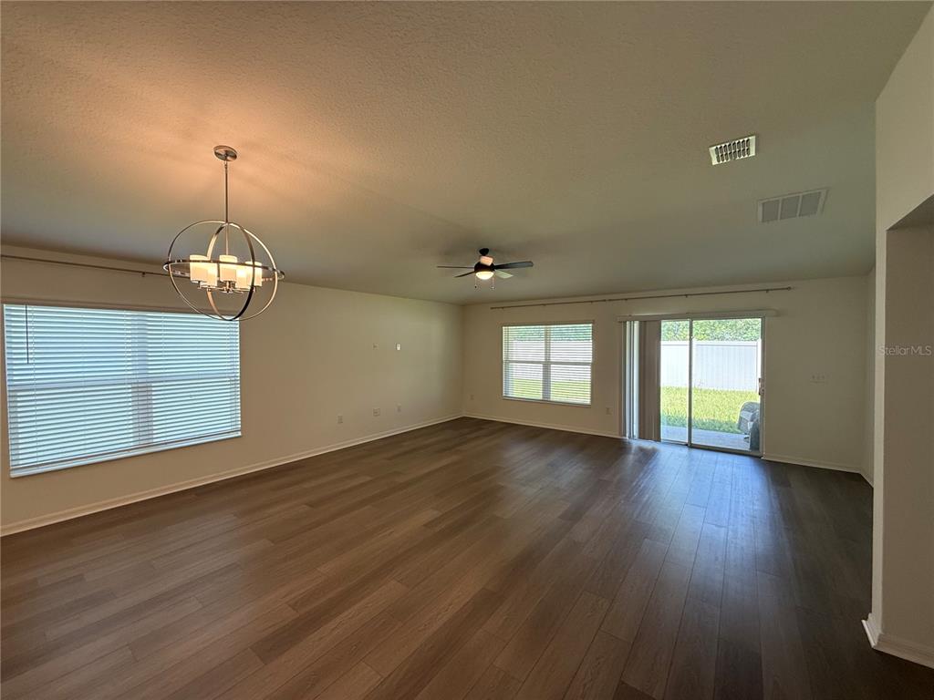An empty living room features light-colored walls, wood-look flooring, a ceiling fan, and a chandelier — 13085 THATCH PALM WAY, ORLANDO, FL