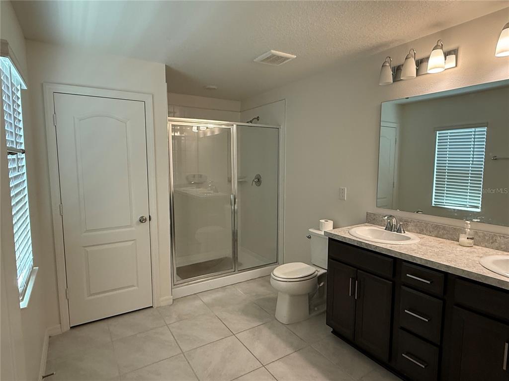 A bathroom features a glass-enclosed shower, a toilet, and a dark wood vanity with sinks — 13085 THATCH PALM WAY, ORLANDO, FL