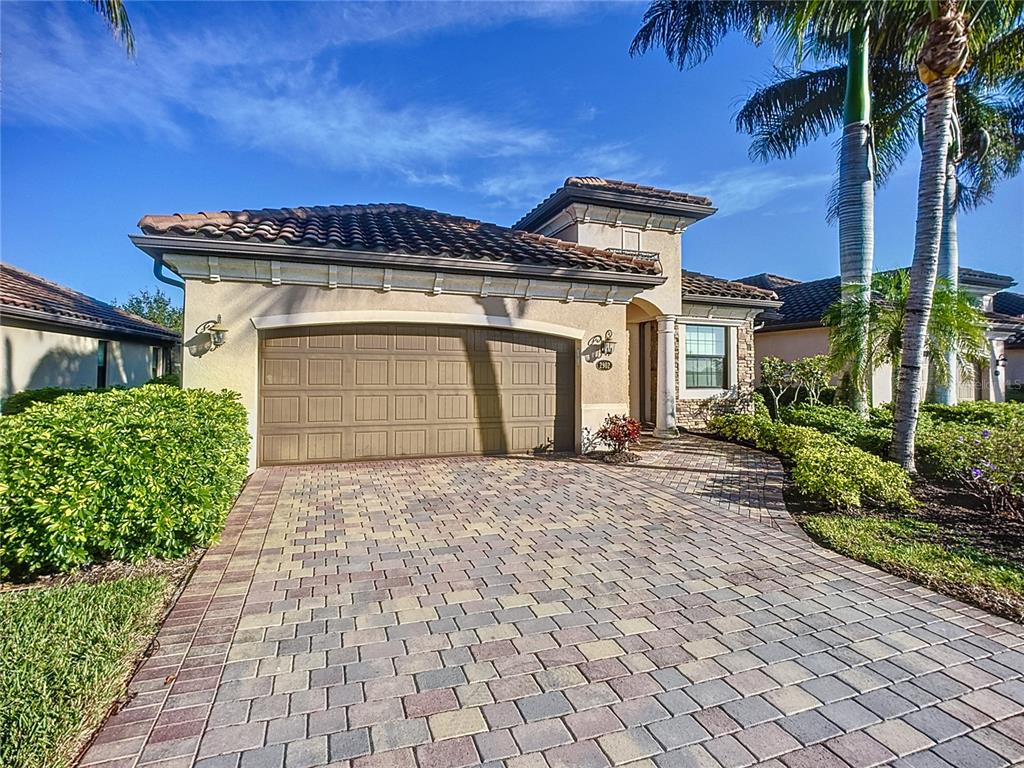 A single-story house with a tiled roof, beige stucco exterior, and a paved driveway — 2902 AVIAMAR CIRCLE, NAPLES, FL