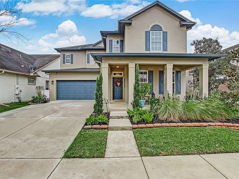 A two-story suburban house with a beige stucco exterior, a front porch, and a garage — 7332 COLBURY AVENUE, WINDERMERE, FL