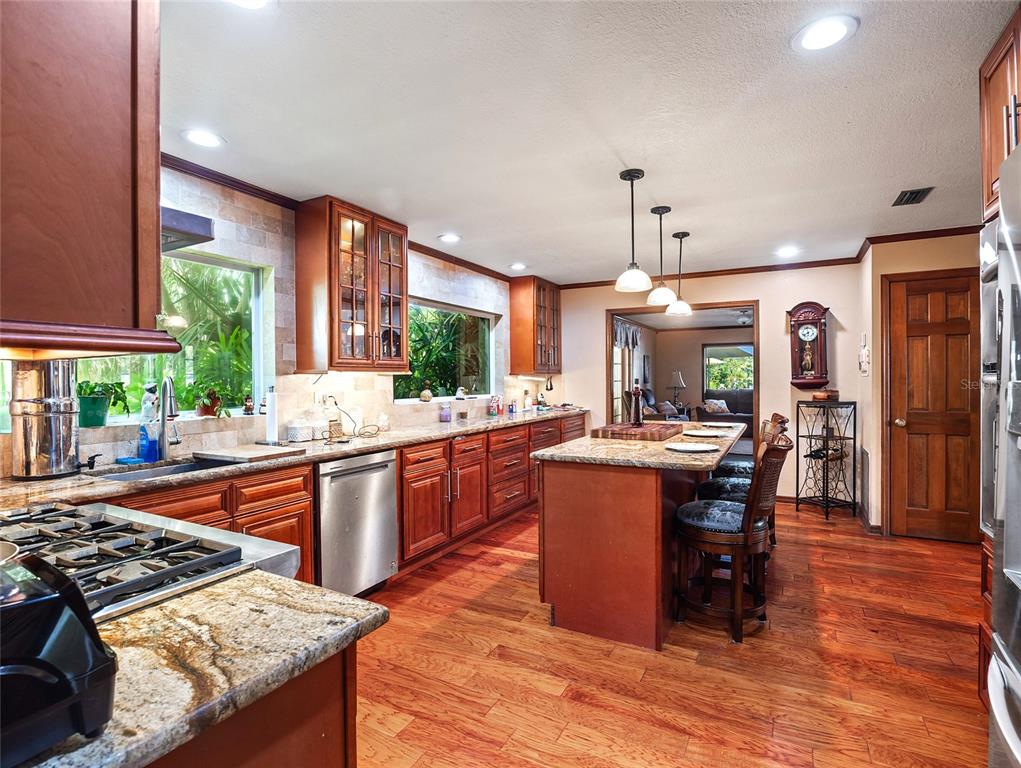 A kitchen with wood cabinets, granite countertops, a center island, and hardwood flooring — 15733 TOWER VIEW DRIVE, CLERMONT, FL