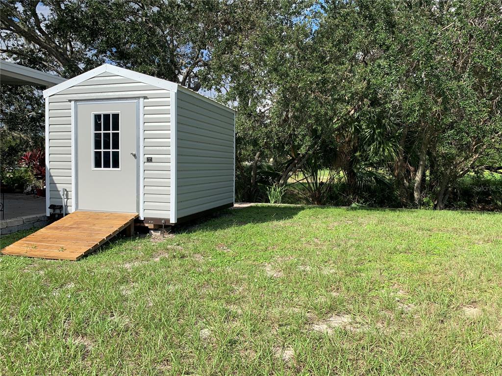 A light-colored storage shed with a wooden ramp sits on a grassy lawn — 223 N SAINT GEORGE CIRCLE, APOLLO BEACH, FL