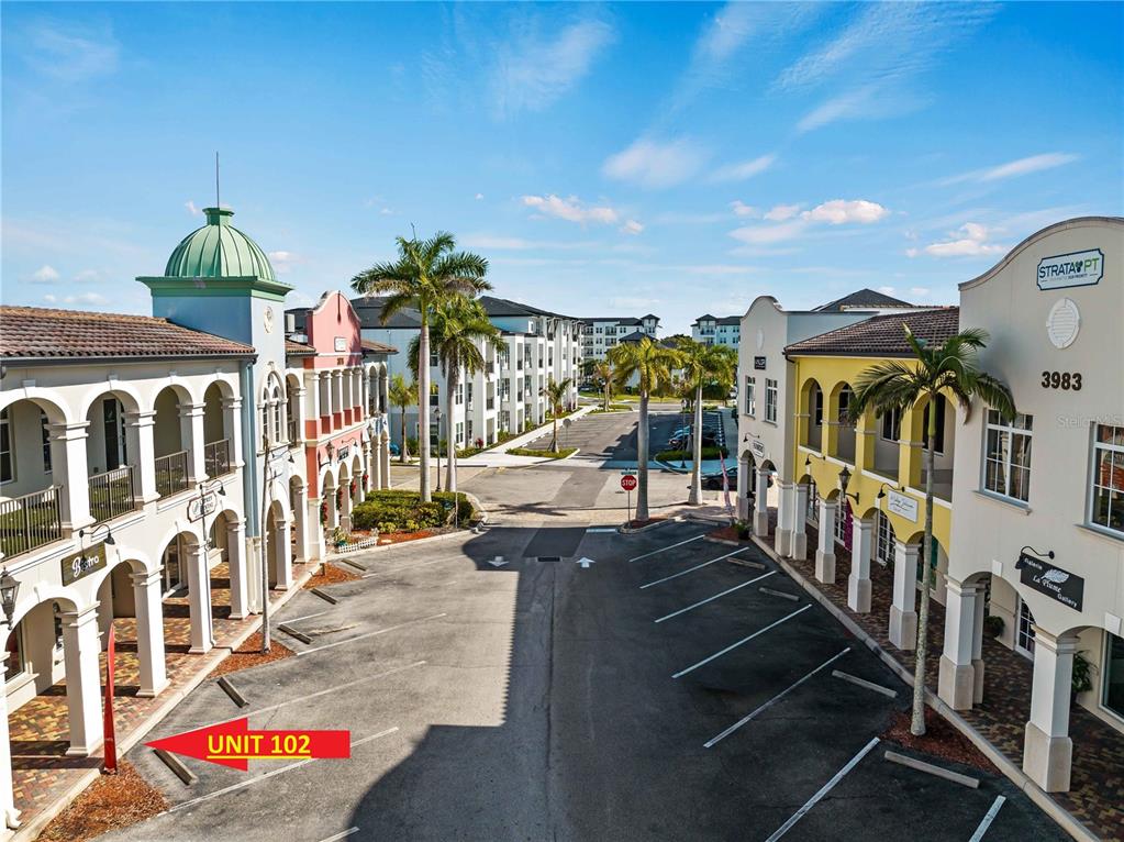 An outdoor view of a commercial plaza with two-story buildings and a parking lot — 3976 DESTINATION DRIVE UNIT 102, OSPREY, FL