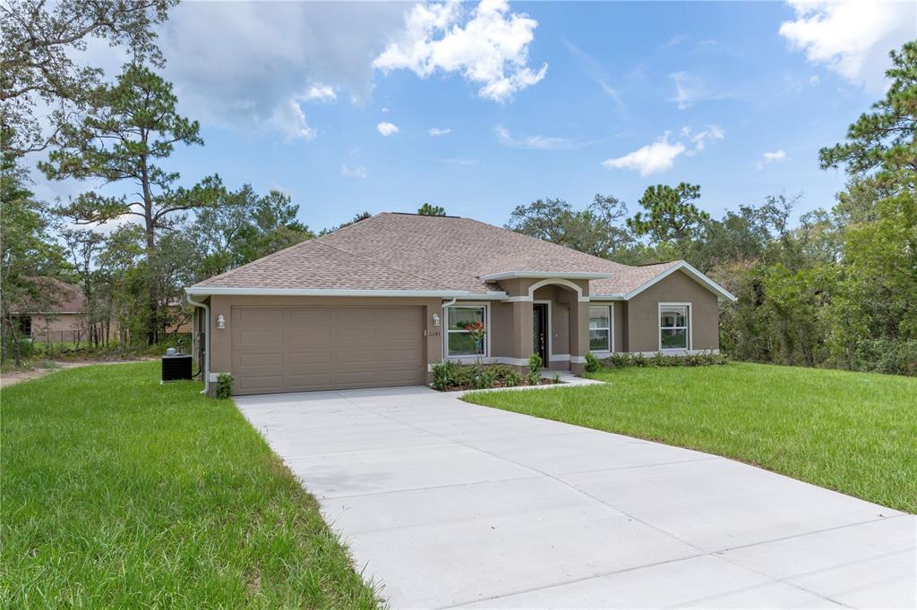A single-story tan house with a two-car garage and a concrete driveway — 13048 KITTIWAKE ROAD, WEEKI WACHEE, FL