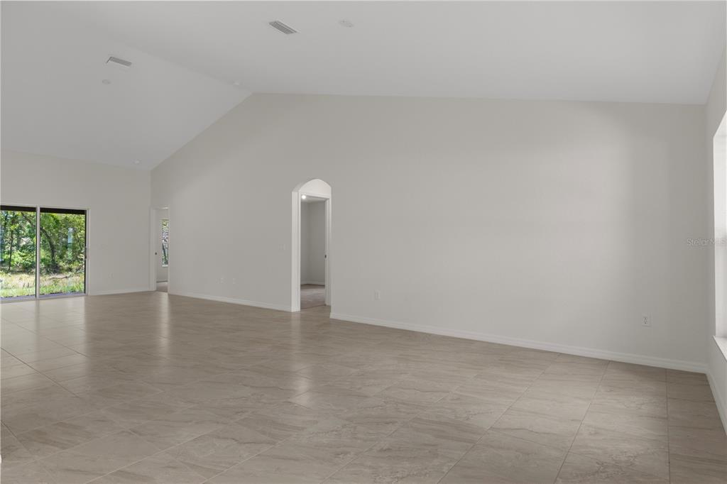 A spacious room with vaulted ceilings, light-colored walls, and large gray floor tiles — 13048 KITTIWAKE ROAD, WEEKI WACHEE, FL