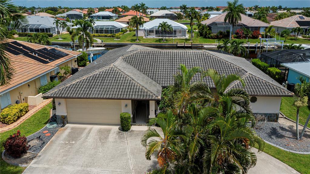 An aerial view of a single-story house with a tiled roof and a concrete driveway — 1205 VIA TRIPOLI, PUNTA GORDA, FL