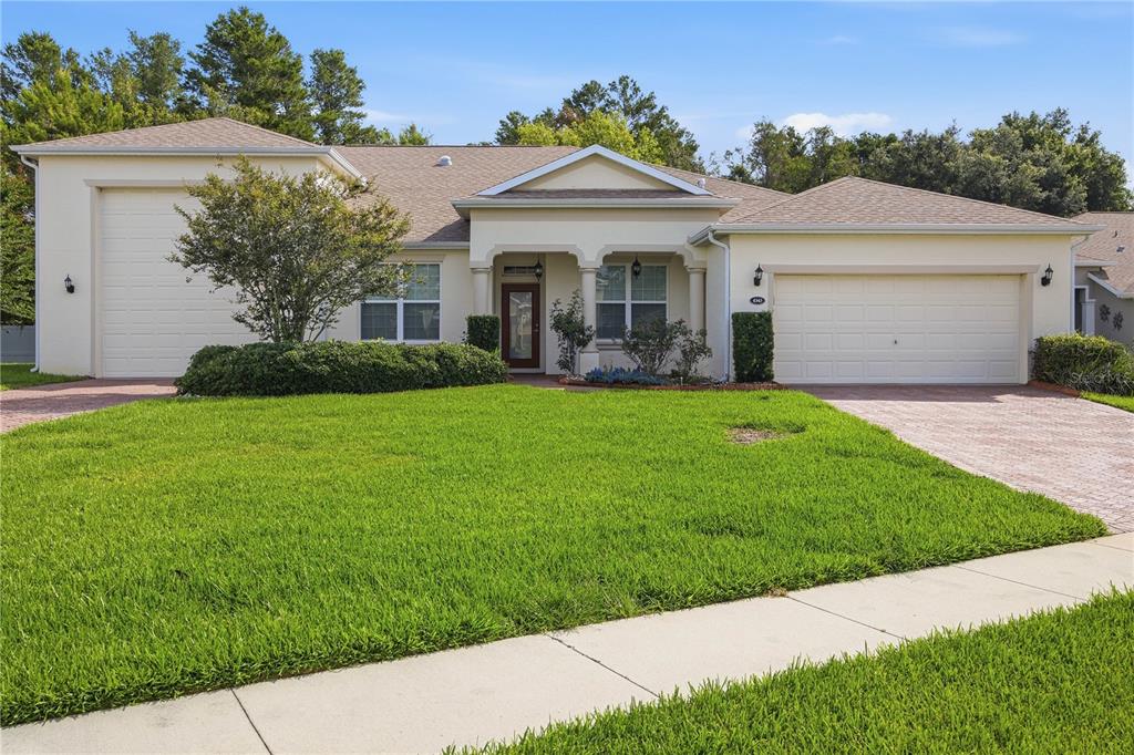 A single-story house with a beige stucco exterior, two garage doors, and a front lawn — 4343 HERITAGE TRAIL, LEESBURG, FL