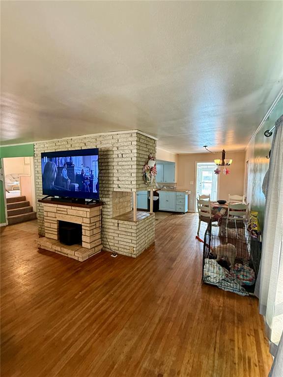 A living room features a brick fireplace with a mounted television and hardwood flooring — 104 13TH STREET SE, WINTER HAVEN, FL