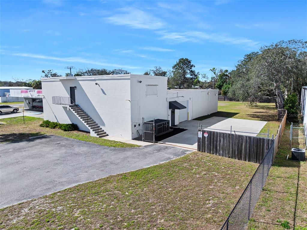 An exterior view of a white commercial building with an outdoor staircase and fenced lot — 974 S NOVA ROAD, ORMOND BEACH, FL