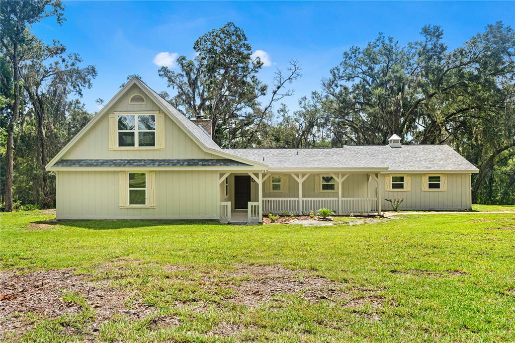 A two-story, light green house with a covered porch sits on a grassy lawn — 3270 ENDSLEY ROAD, BROOKSVILLE, FL
