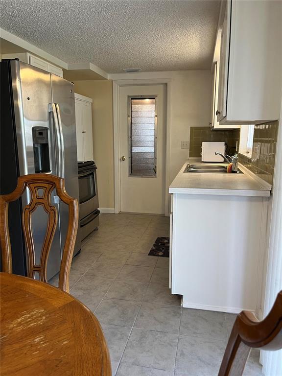 A kitchen features white cabinets, a double-basin sink, and olive green tiled backsplashes — 3632 PENSDALE DRIVE, NEW PORT RICHEY, FL