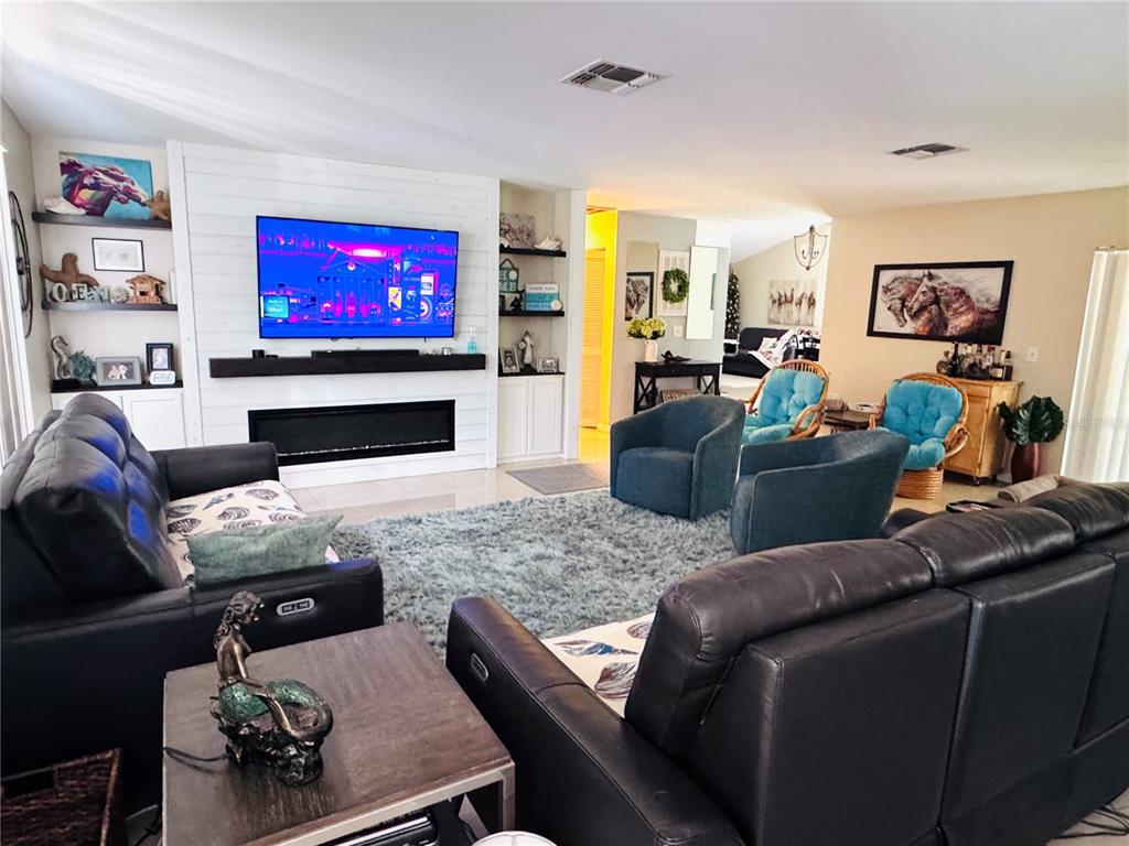 A living room features a white shiplap fireplace wall, dark leather sofas, and blue armchairs — 7590 N CAESAR POINT, DUNNELLON, FL