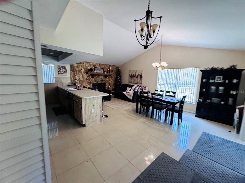 An open-concept living and dining area features tile flooring, a stone fireplace, and a kitchen island — 7590 N CAESAR POINT, DUNNELLON, FL