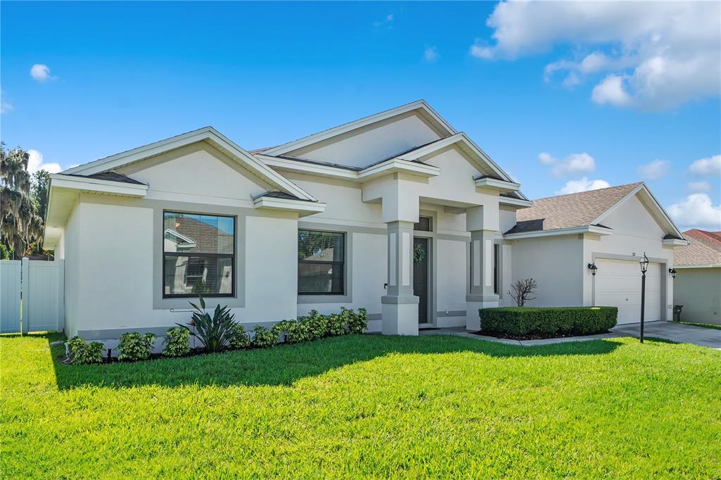 A bright entryway features white walls, wood-look flooring, a front door with sidelights, and an arched opening — 525 GANDHI DRIVE, LAKELAND, FL