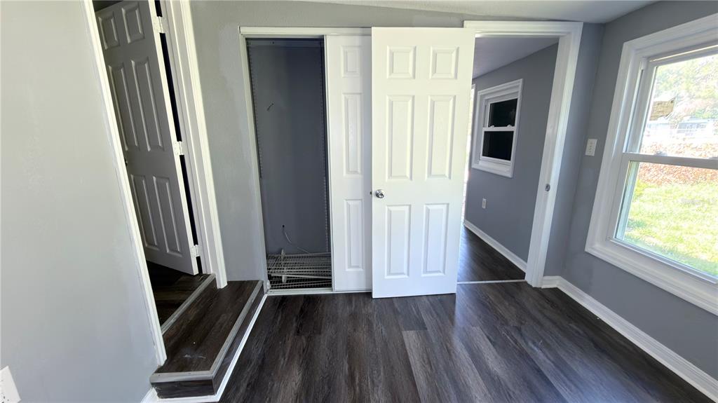 A room with dark wood-look flooring, gray walls, a closet, and two doorways — 11772 SE 99TH TERRACE, BELLEVIEW, FL