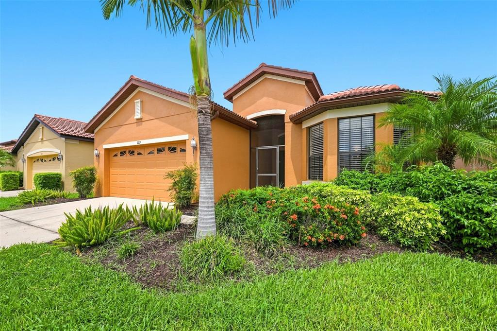 A single-story orange stucco house with a two-car garage and a palm tree in front — 229 SILVER FALLS DRIVE, APOLLO BEACH, FL