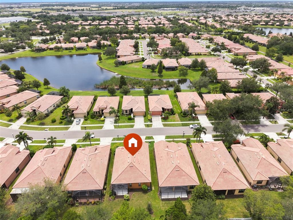 An aerial view shows a row of suburban houses with tiled roofs near a lake — 229 SILVER FALLS DRIVE, APOLLO BEACH, FL