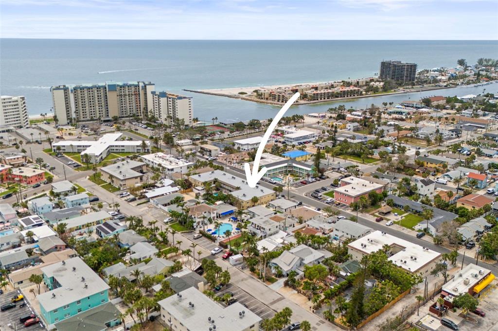 An aerial view shows a multi-story apartment complex with a pool in a coastal neighborhood — 600 71ST AVENUE UNIT 18, ST PETE BEACH, FL