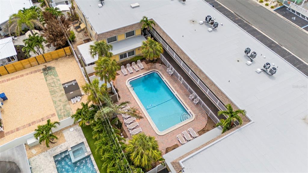 An aerial view shows a swimming pool and patio area between two multi-story buildings — 600 71ST AVENUE UNIT 18, ST PETE BEACH, FL