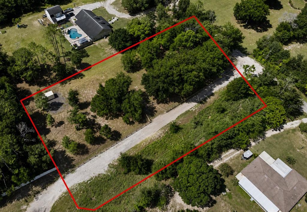 An aerial view shows a rectangular plot of land outlined in red with trees and gravel — 0 RAISER RD, DADE CITY, FL