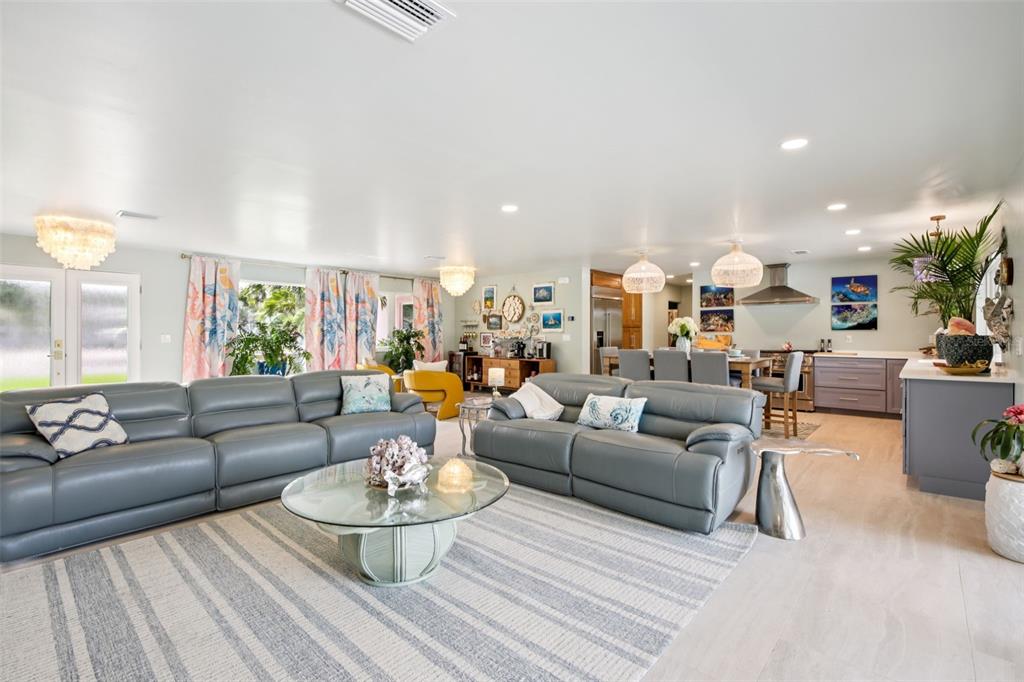 A spacious open-concept living room features gray leather sofas, a glass coffee table, and kitchen — 613 BUTTONWOOD DRIVE, LONGBOAT KEY, FL
