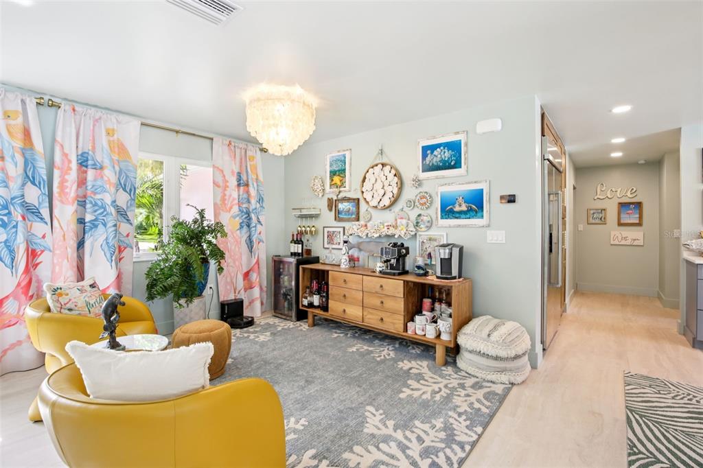 A living room features yellow armchairs, a wooden sideboard, and a gallery wall on light-blue walls — 613 BUTTONWOOD DRIVE, LONGBOAT KEY, FL