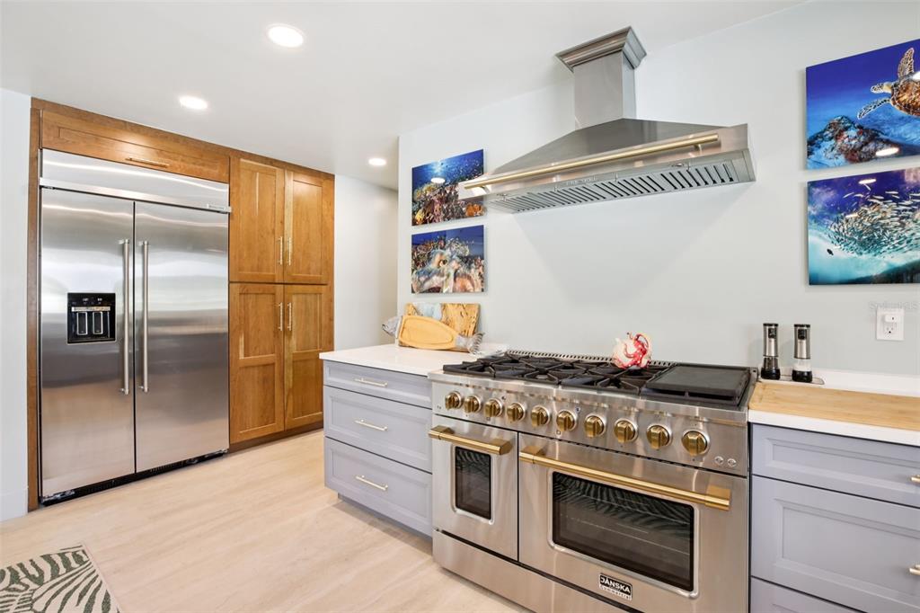 A kitchen features light gray cabinets, a stainless steel range, and wood-toned pantry cabinetry — 613 BUTTONWOOD DRIVE, LONGBOAT KEY, FL