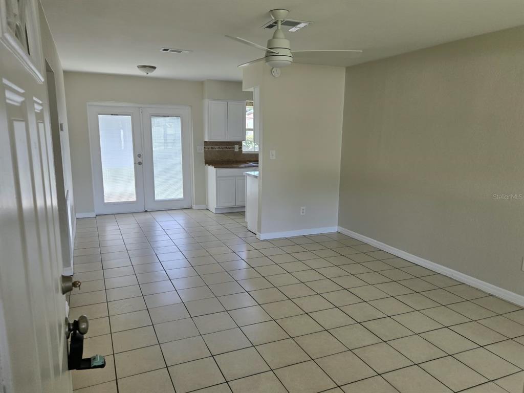 A tiled living area features a ceiling fan, white cabinets, and double glass doors — 5772 94TH AVENUE N, PINELLAS PARK, FL